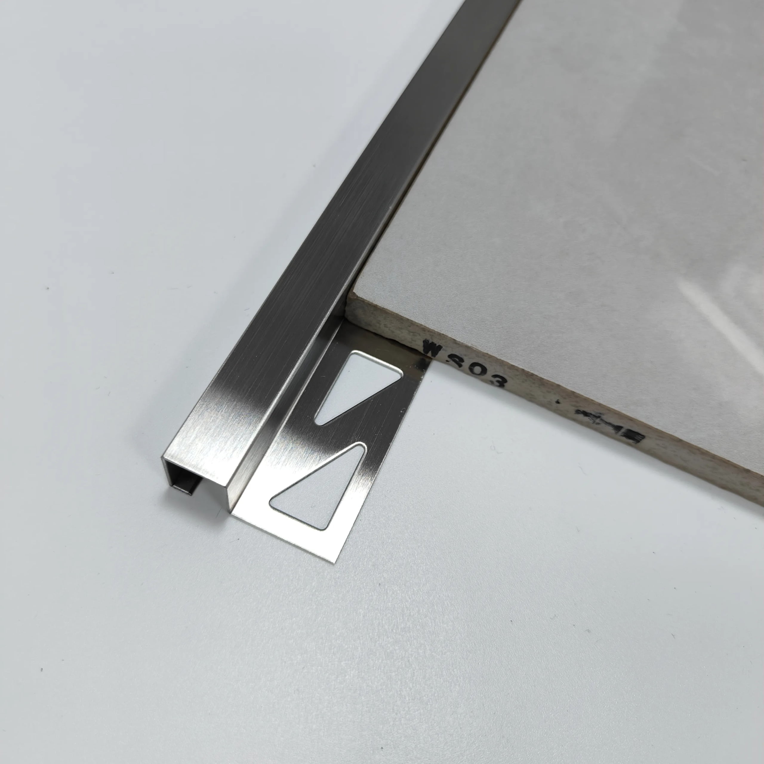 Square-edge metal trim beside the exposed edge of a tile sample