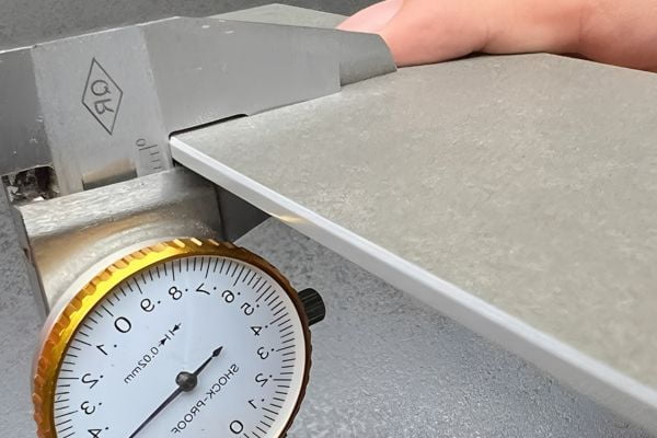 Caliper measuring the thickness of a tile sample